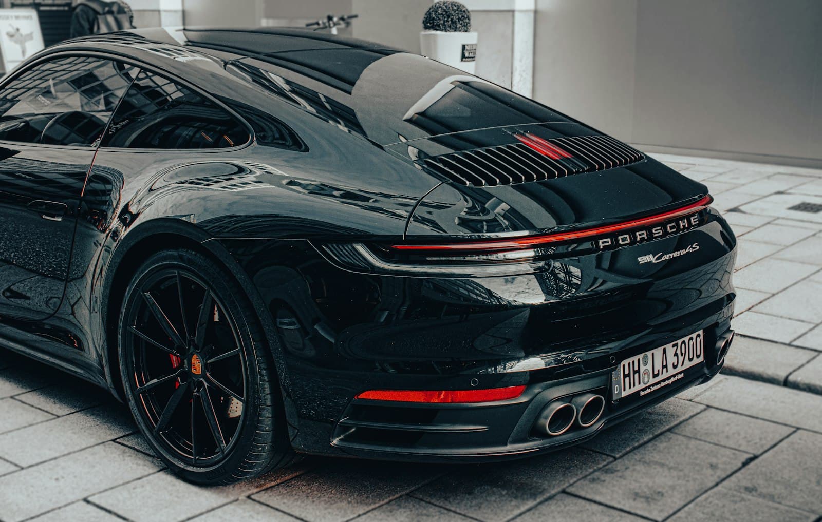 Rear three-quarter view of a black Porsche 911 with a deep, reflective finish