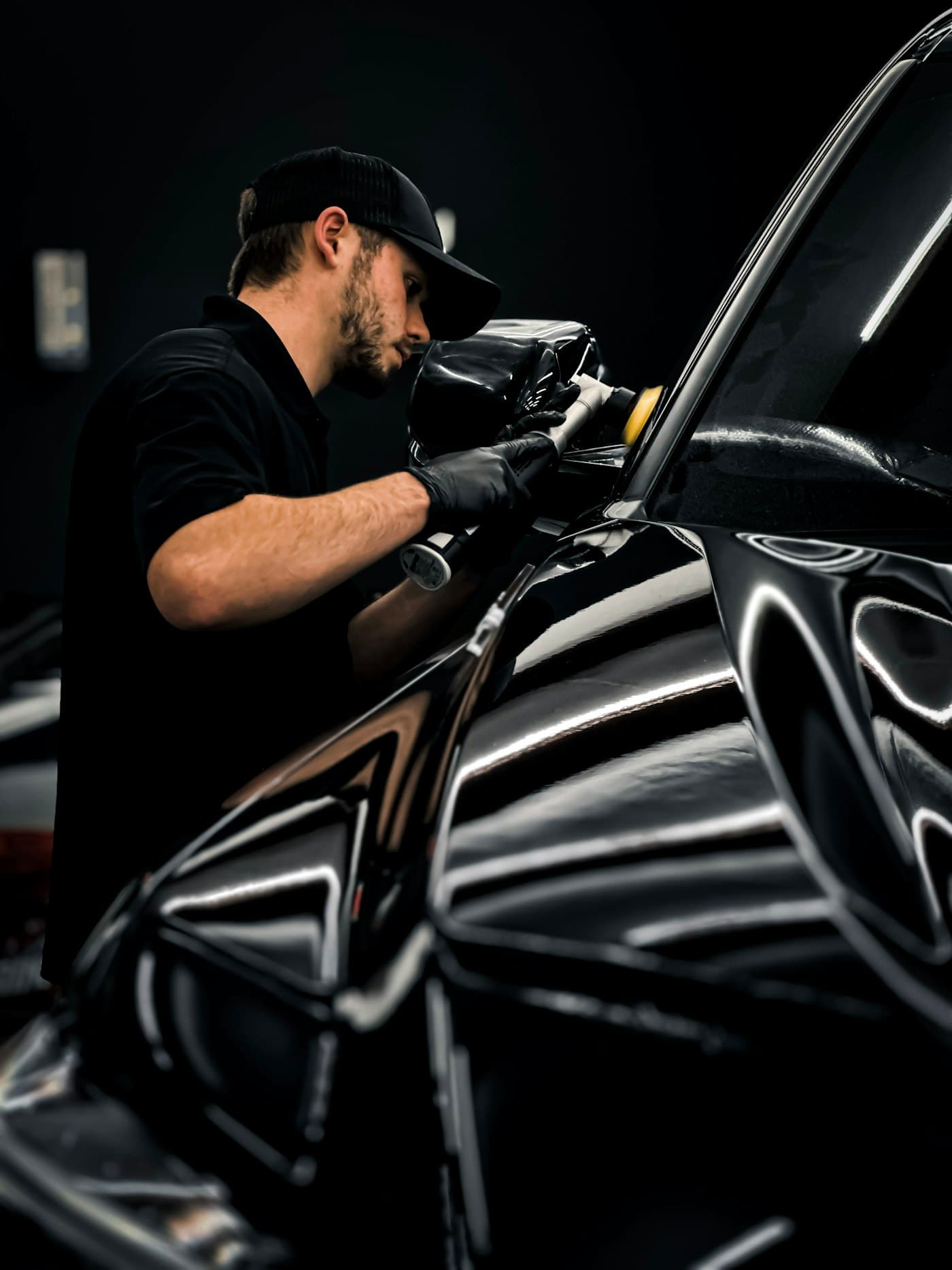 Detailer machine polishing the gloss black paint of a vehicle